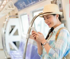 Woman in a train looking at her phone and smiling
