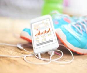 fitness app on a phone, headphones and trainers